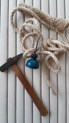 An old hammer, jute twine, and jute thread are laid out on a light plank table