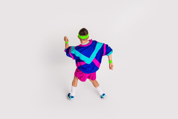 Energetic young man in colorful retro sportswear doing exercise on white background