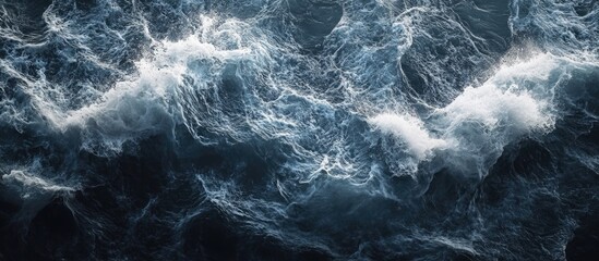 Dark blue ocean waves with white frothy crest form a dynamic texture creating a captivating visual effect suitable for various design projects