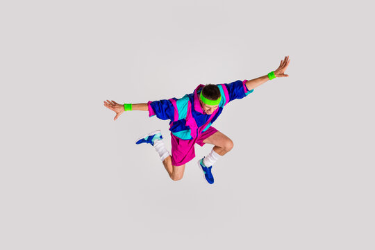 Energetic young man in retro sportswear jumping against light gray background - Powered by Adobe