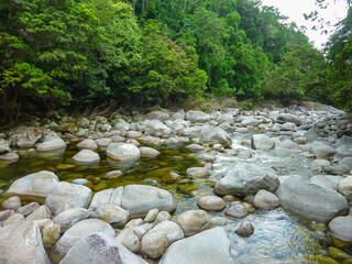 Stream meandering through smooth granite boulders at Mossman Gorge in Daintree Rainforest. Lush tropical vegetation frames ancient riverbed. Serene wilderness Cape Tribulation, Queensland, Australia