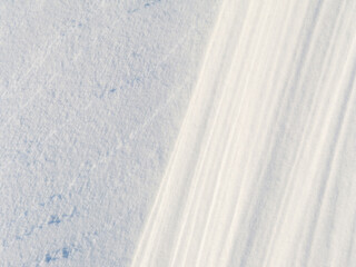 Obraz premium Beautiful winter background with snowy ground. Natural snow texture. Wind sculpted patterns on snow surface.