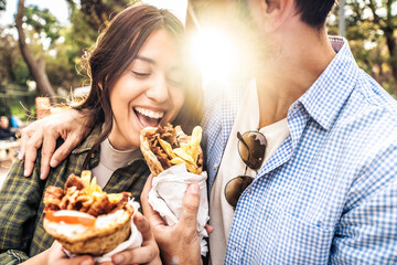 Happy couple eating gyros souvlaki  wrapped in a pita, greek food - Smiling girl and guy bite Doner...
