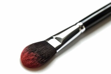 Red tipped makeup brush lies on a white background, ready for beauty application
