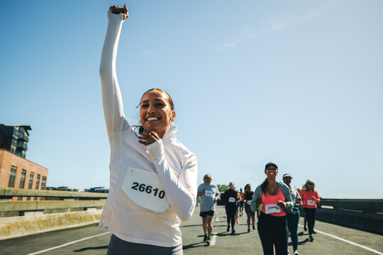 Multiracial female runner celebrating victory in a lively race event
