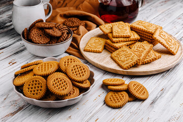 Assorted cookies arranged on a rustic wooden table with tea and a cozy atmosphere perfect for sharing