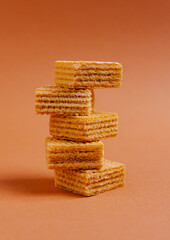Stack of crispy wafers on a warm orange background creating a visually pleasing dessert display