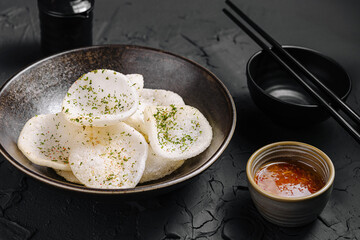 Crispy snack served with dipping sauce in a stylish bowl on a textured surface