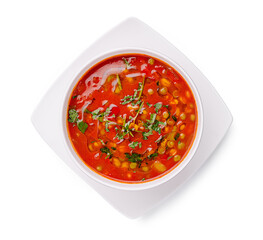 Warm red soup with fresh herbs and vegetables served in a modern bowl at a cozy kitchen table