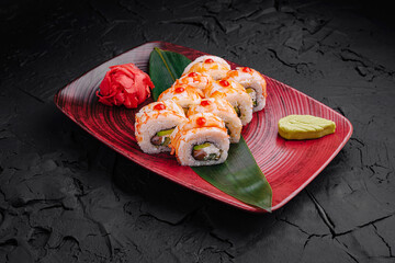 Delicious sushi rolls beautifully presented on a vibrant plate with a touch of greenery and garnishes