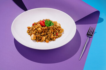 Colorful couscous salad with vegetables and chicken served on a vibrant background
