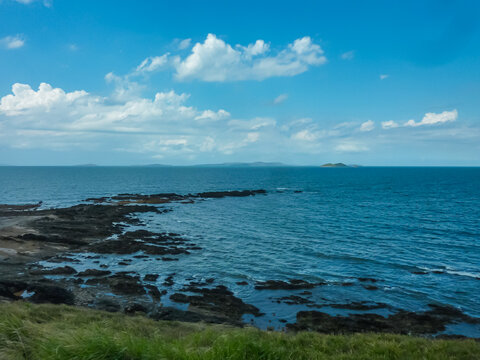 Coastal view from Emu Park, Australia, looking out over blue waters of Capricorn Coast. Distant, hazy form of Lambay Island can be seen on horizon, adding depth to seascape. Coastline Pacific Ocean