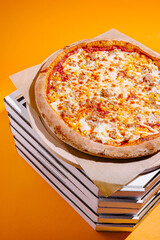 Pizza on top of stacked boxes with an orange background showcasing its delicious toppings