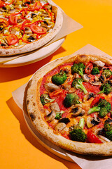 Freshly baked vegetable pizzas on golden orange background with vibrant toppings waiting to be enjoyed