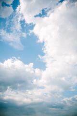 Bright blue sky with fluffy white clouds scattered across, forming dynamic shapes. Sunlight filters through the clouds, creating depth and contrast in a natural outdoor setting.  
