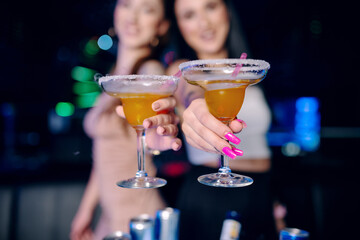 Two girls drink in night bar