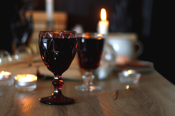 Books, lit candles, red wine, snacks and various deocration on the table. Dark academia or Halloween concept. Selective focus.
