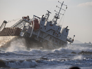 The ship stranded and wrecked. Stormy sea in overcast weather waves crash on a pier near the shore...