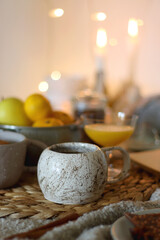 Books, e-reader, tea, orange juice, fruit, snacks, yarn, blanket and lit candles on the table. Autumn or winter hygge at home. Selective focus.