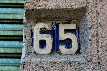 Numéro 65. Chiffres blancs sur fond bleu. Numéro de rue.