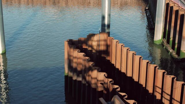 Industrial shot of rusted sheet pile walls in a waterfront construction project surrounded by calm water on a sunny day