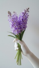 Obraz premium Elegant bouquet of purple flowers held by a white glove