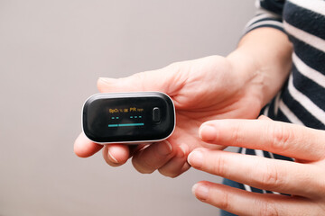 A woman checking her heart rate and oxygenation level. Monitoring Blood Oxygen Levels and Pulse Rate