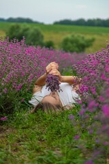 Woman in lavender field. Happy carefree woman in white dress and hat walking through lavender field