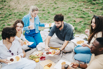 A group of multiracial friends enjoying a picnic in nature on a cloudy day. They are sharing food, socializing, and creating joyful memories in an outdoor setting, reflecting togetherness and