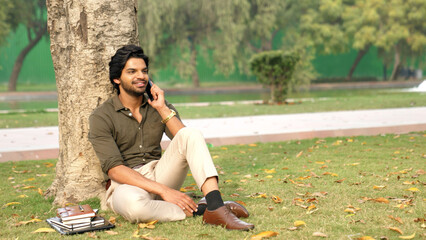 Naklejka premium Indian Man Talking on Phone Under a Tree