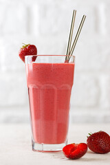 Strawberry smoothie or milkshake drink with coconut cream and green buckwheat in a tall glass. Lactose and sugar free. Vertical orientation.