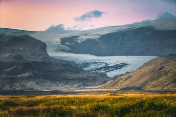 Vue panoramique sur un glacier islandais descendant des montagnes sous une lumière dorée....