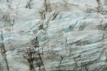 Détail d’un glacier en Islande, révélant les nuances bleutées de la glace et les strates sombres de sédiments. Texture unique et formation naturelle sculptée par le temps et les éléments.