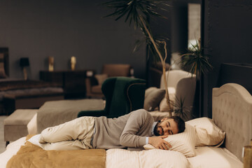 a man is testing and lying on a bed in a furniture store