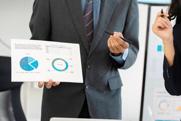 Businessman holding financial report with graphs during a presentation.