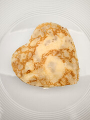 Delicious heart shaped crepes, pancake resting on a white plate, perfect for a romantic breakfast or special occasion for Mother's Day Valentines copy space