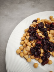 Chickpeas scattered with dried cranberries, presenting vibrant color contrast and healthy wholesome snacking on minimalist white plate healthy dinner for Galentines day