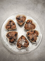Chocolate heart shaped blueberry muffins dusted with powdered sugar, nestled on delicate glass plate, showcasing romantic dessert with irresistible charm for Mother's Day Valentines copy space