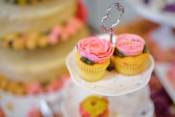 Close-Up of Elegant Cupcakes with Pink Rose Frosting on Tiered Stand