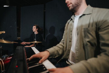 Two musicians practicing in a studio, with one playing drums and the other the keyboard, showcasing...