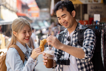 Traveling couple enjoying street food and coffee at a local market.