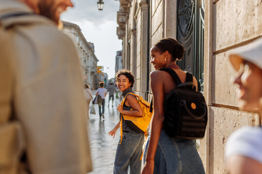 Tourists walking down sunny street in european city during summer vacation