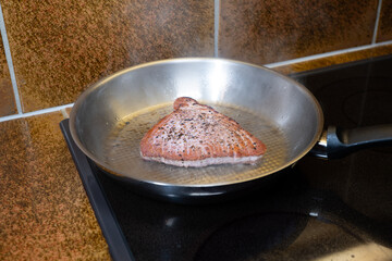 Fresh raw seasoned tuna steak slice being cooked in an aluminum frying pan. Close up shot, no people