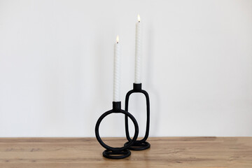 Beautiful decorative LED candles on wooden table. Candles and stylish black loft candlesticks on...