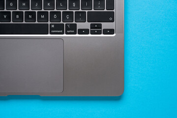 Top view of corner and keyboard of laptop on blue table