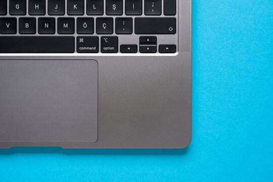 Top view of corner and keyboard of laptop on blue table