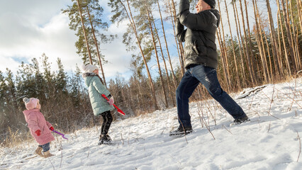 Playful family enjoying snowball fight in snowy winter park