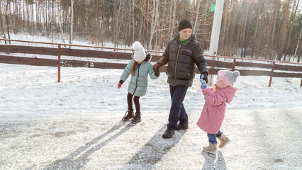 Little girls with her grandfather walking in park on snowy winter day