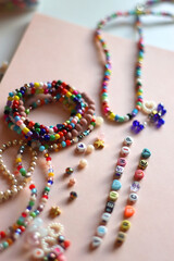 Friendship bracelet spelled with letter beads. Colorful handmade bracelets and various beads. Selective focus, pink background.