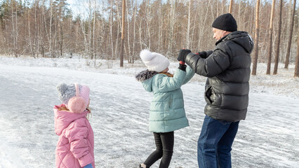 Little girls with her grandfather walking in park on snowy winter day